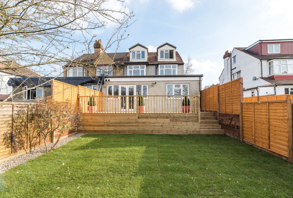 Rear house extension with raised timber decking, landscaped garden, and modern architectural design created by AA Drafting Solutions.